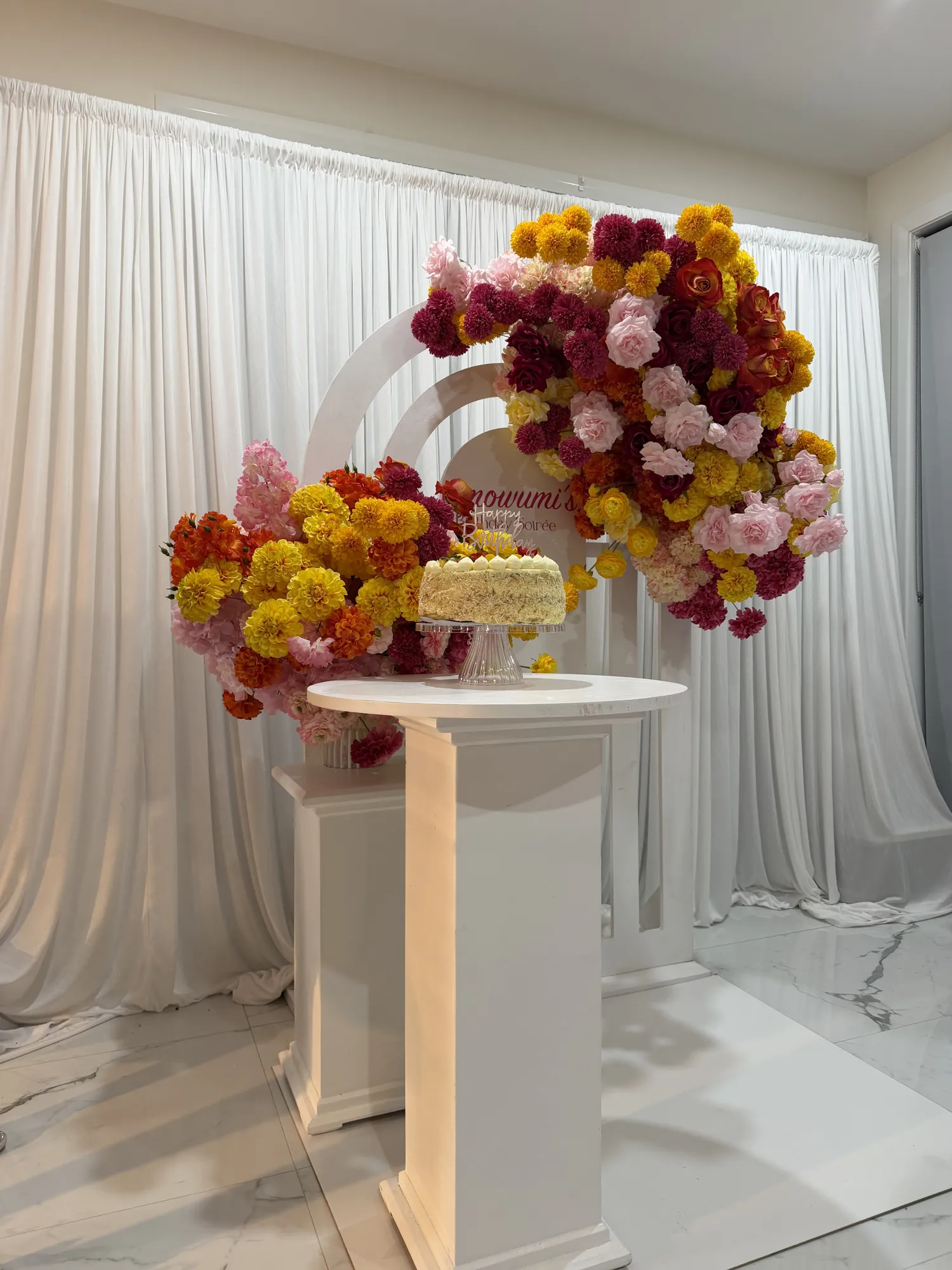 A three-tier white cake with red and white flowers and a marquee 30, on a glass stand.