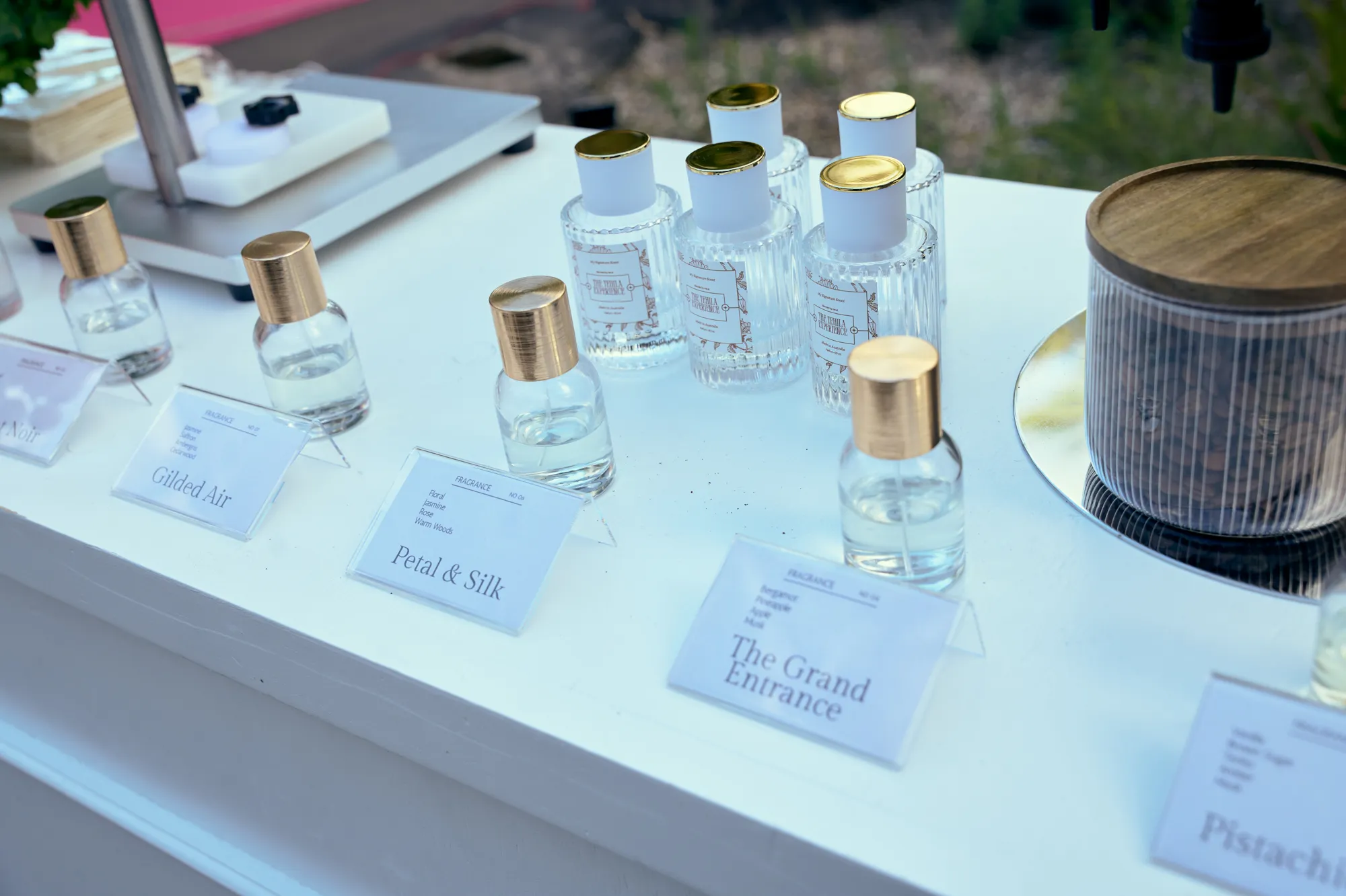 A white fragrance bar with rows of scent bottles, gold-rimmed trays, and a small vase of flowers.