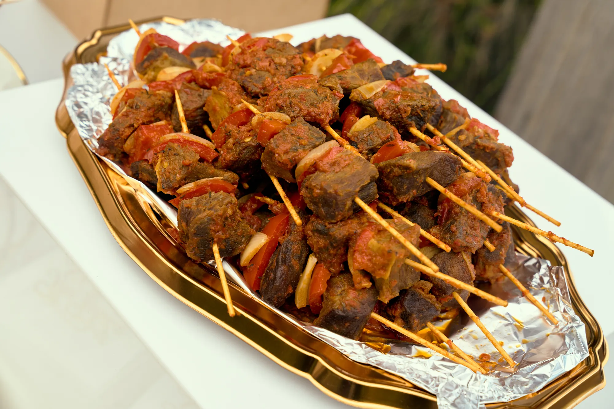 A three-tier stand of grilled skewers with red and yellow peppers.