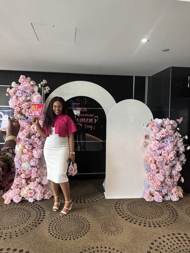 White arch backdrop with pink floral columns at a corporate celebration