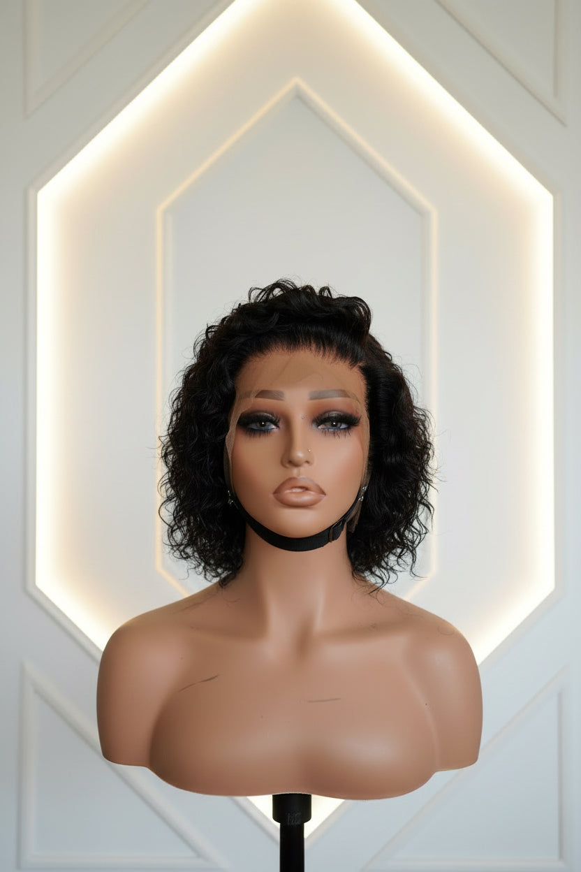 A short dark pixie cut in profile, worn with a white top.